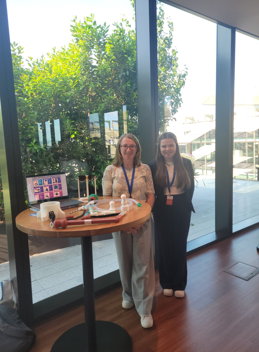 Two presenters standing beside a table displaying assistive devices.